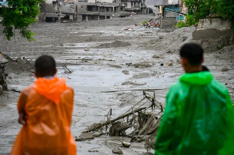 Twee mensen kijken naar de ravage van de overstromingen in Nepal